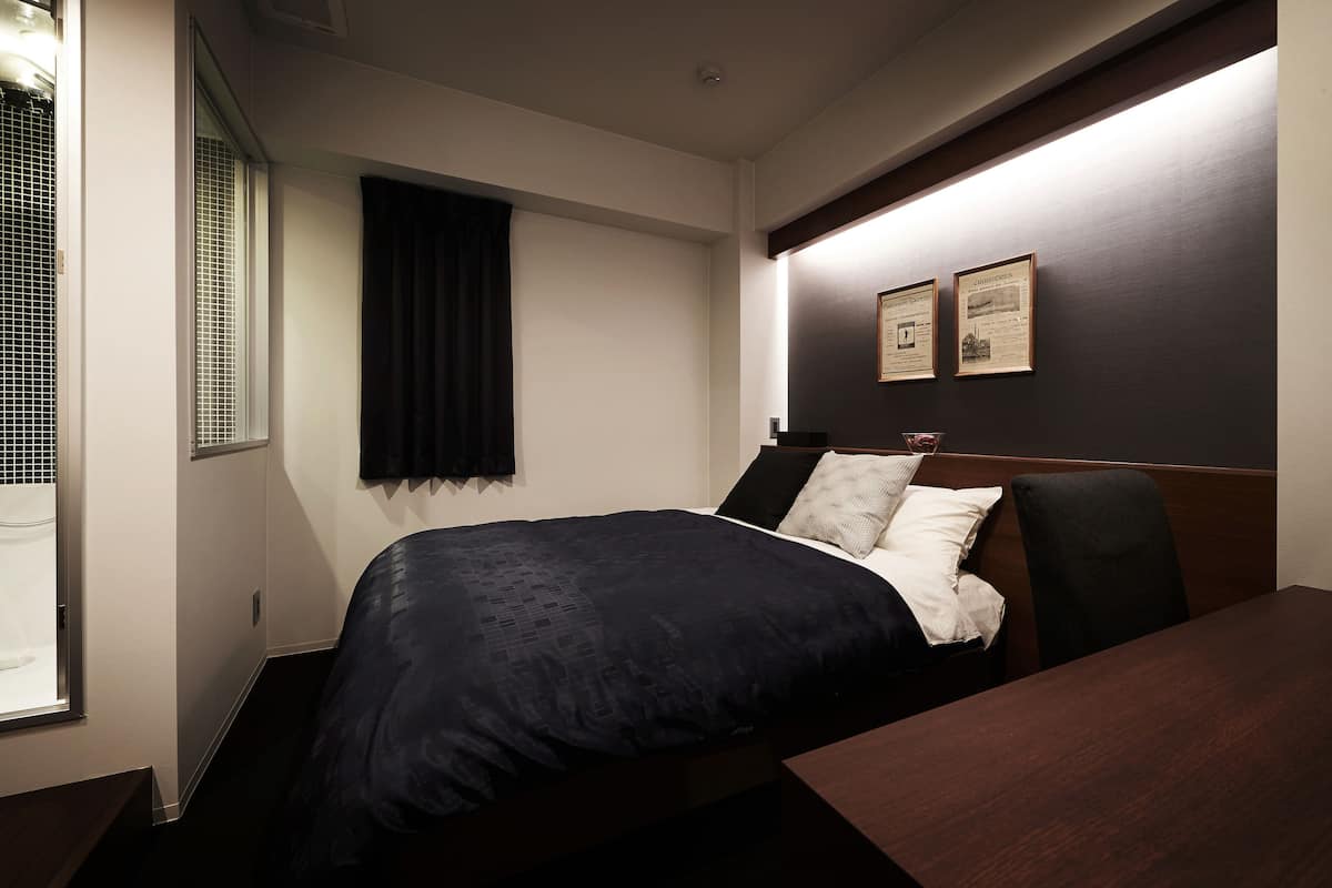 Una habitación de hotel con una cama, un escritorio y dos cuadros en la pared.