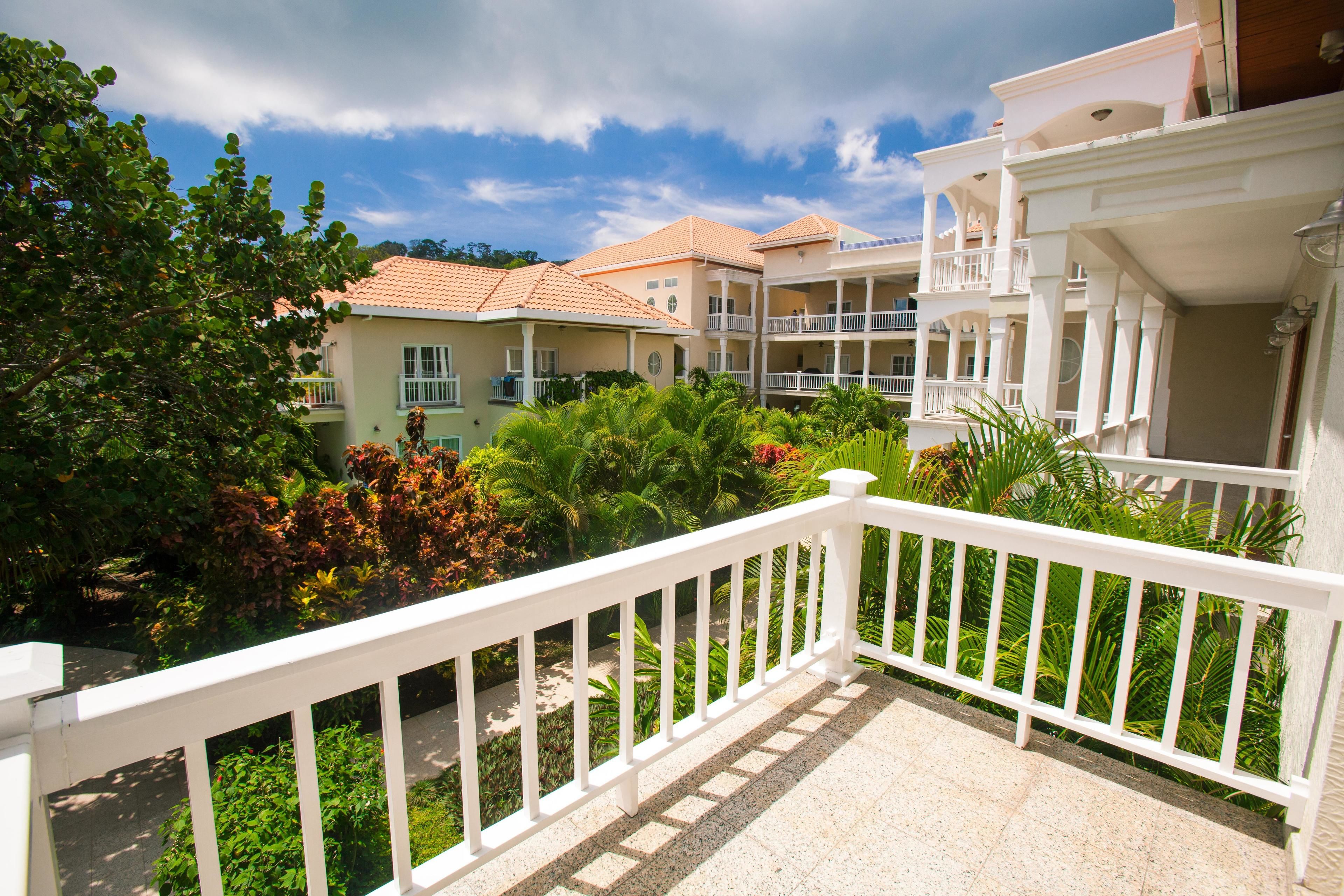 A hotel with multiple balconies, lush greenery, and a clear sky.