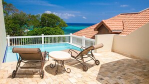 Un balcon avec vue sur une piscine et l’océan.
