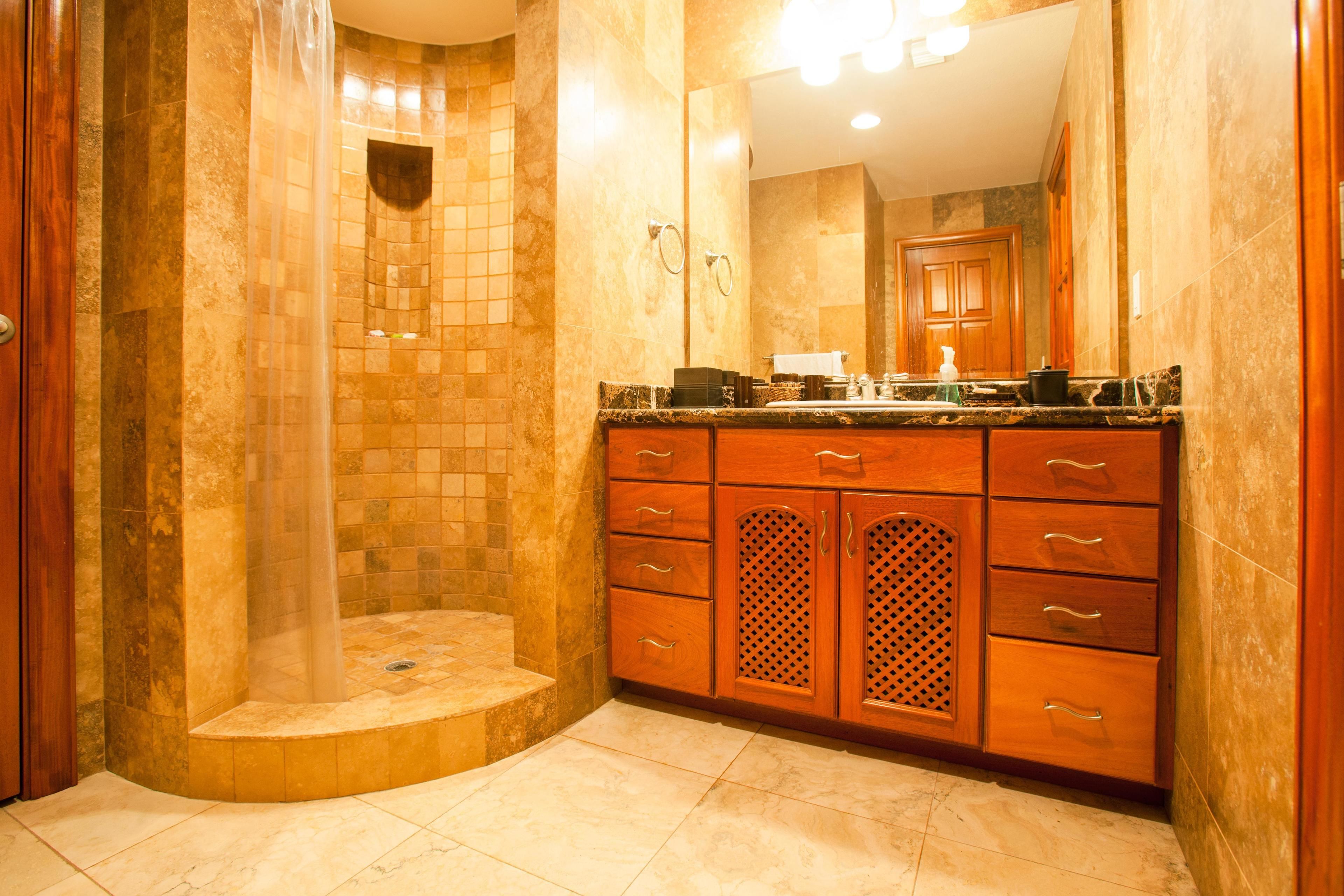 A bathroom with a shower, a sink, and wooden cabinets.