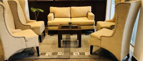 A modern living room with a beige sofa, two armchairs, and a coffee table.