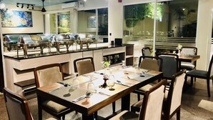 Un restaurante con servicio de buffet, mesas, sillas y un ventilador de techo.