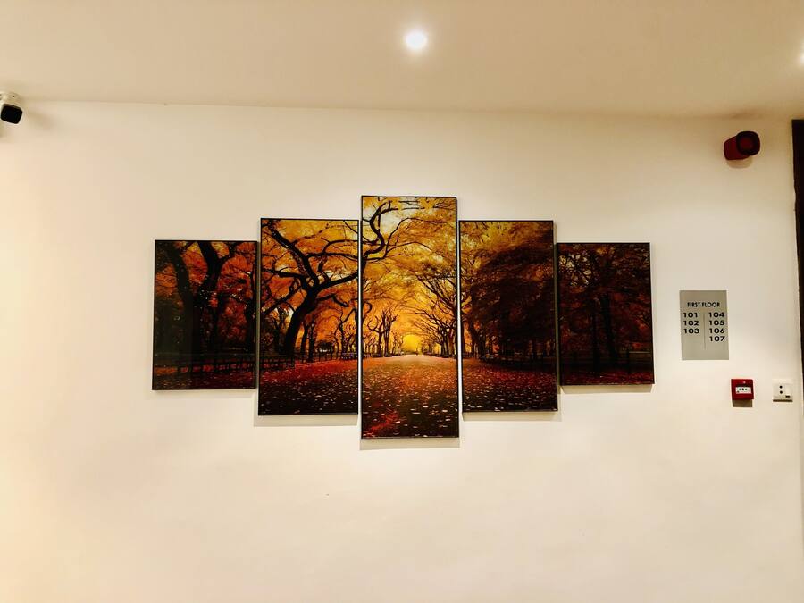 A multi-panel artwork depicting a park scene with autumn leaves, mounted on a white wall.