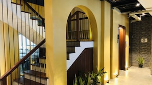 Una escalera moderna con escalones de madera y barandillas metálicas, flanqueada por paredes amarillas y una pared de piedra.