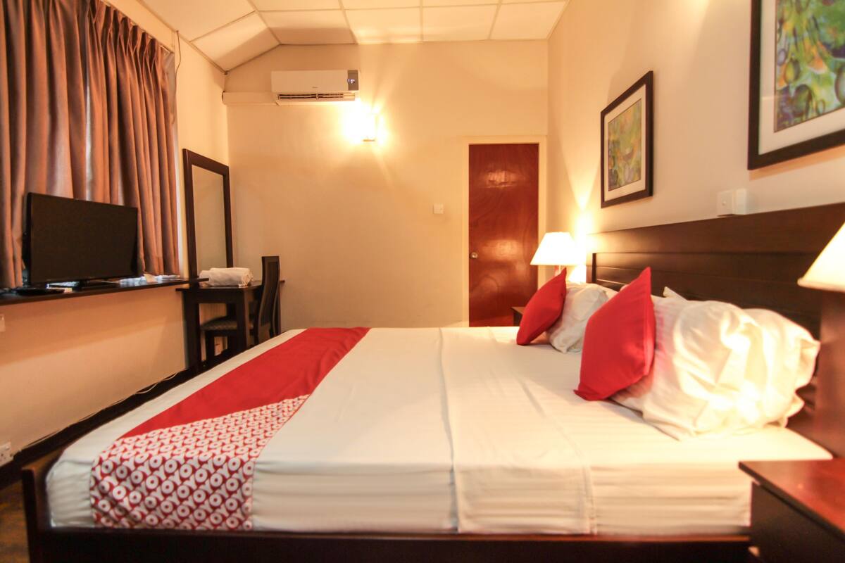 A hotel room with a bed, a television, a desk, and a chair.