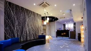 A modern lobby with a marble reception desk, blue seating, and decorative lighting. - The Keong Saik Hotel (Singapore)