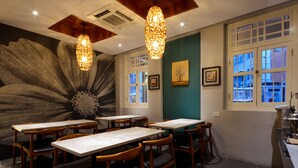 A restaurant interior with wooden tables and chairs, pendant lights, and a large floral mural on the wall. - The Keong Saik Hotel (Singapore)