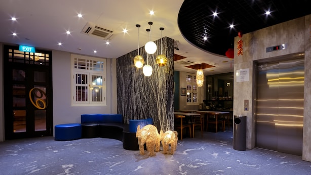 A modern lobby with a curved blue seating area, an elevator, and a reception desk. - The Keong Saik Hotel (Singapore)