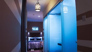 A hotel room with a bed, bedside table, and a sliding door. - The Keong Saik Hotel (Singapore)