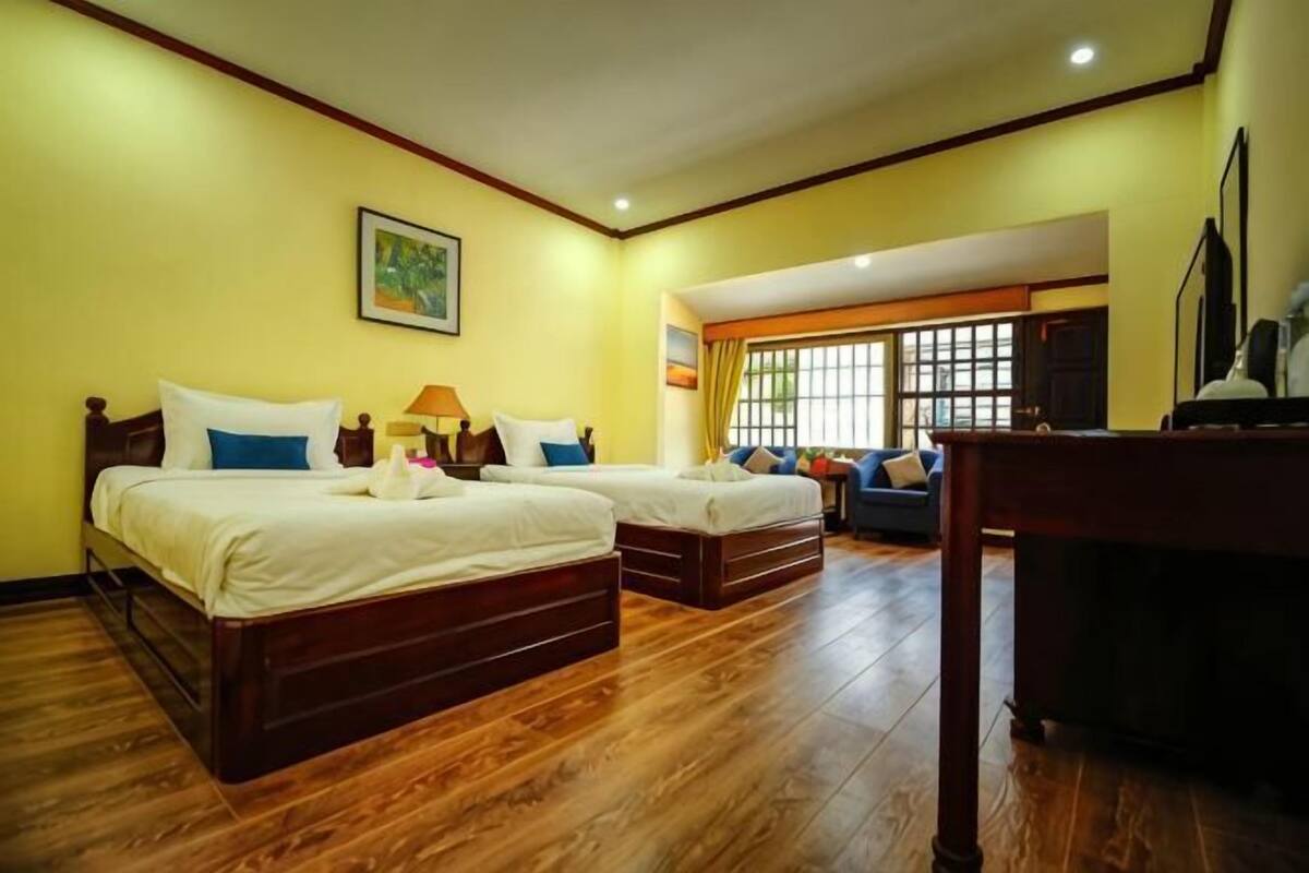 Une chambre d’hôtel avec deux lits, un bureau et une fenêtre.
