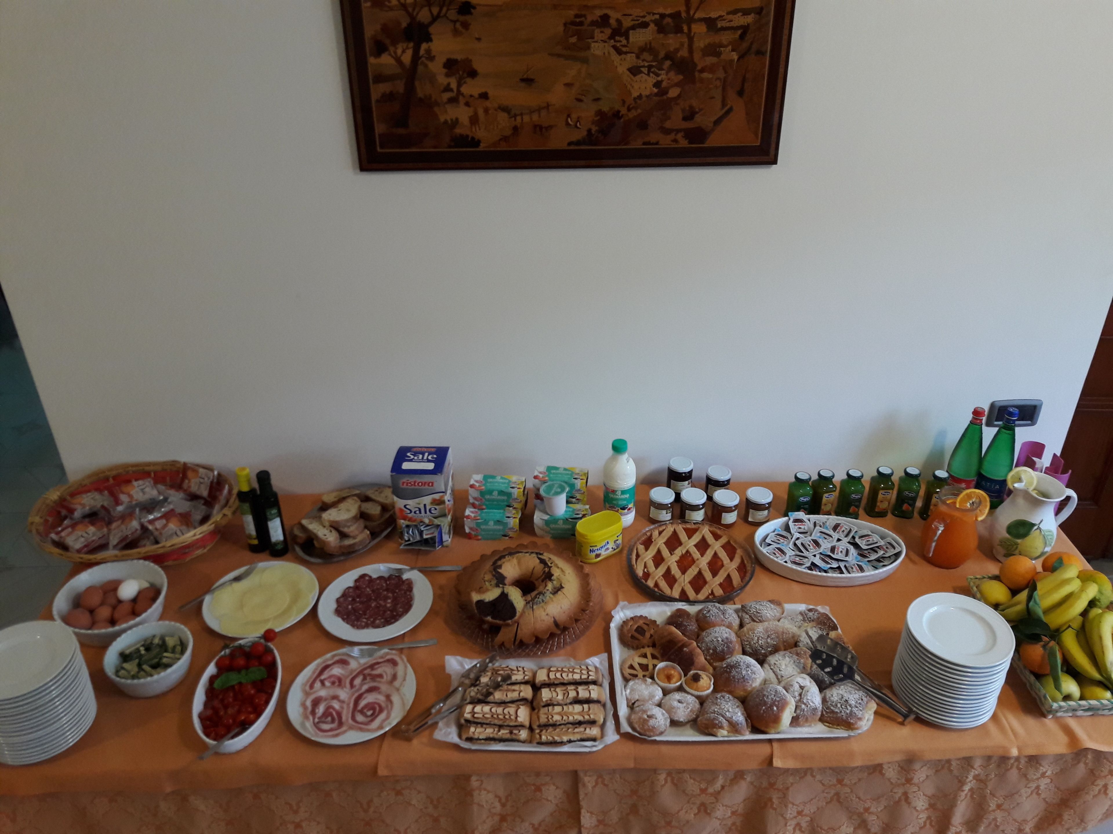 A buffet table with various food items, including pastries, fruits, and condiments.