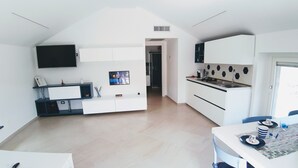 Une cuisine moderne avec des meubles blancs, un four encastré et un coin repas comprenant une table et des chaises.