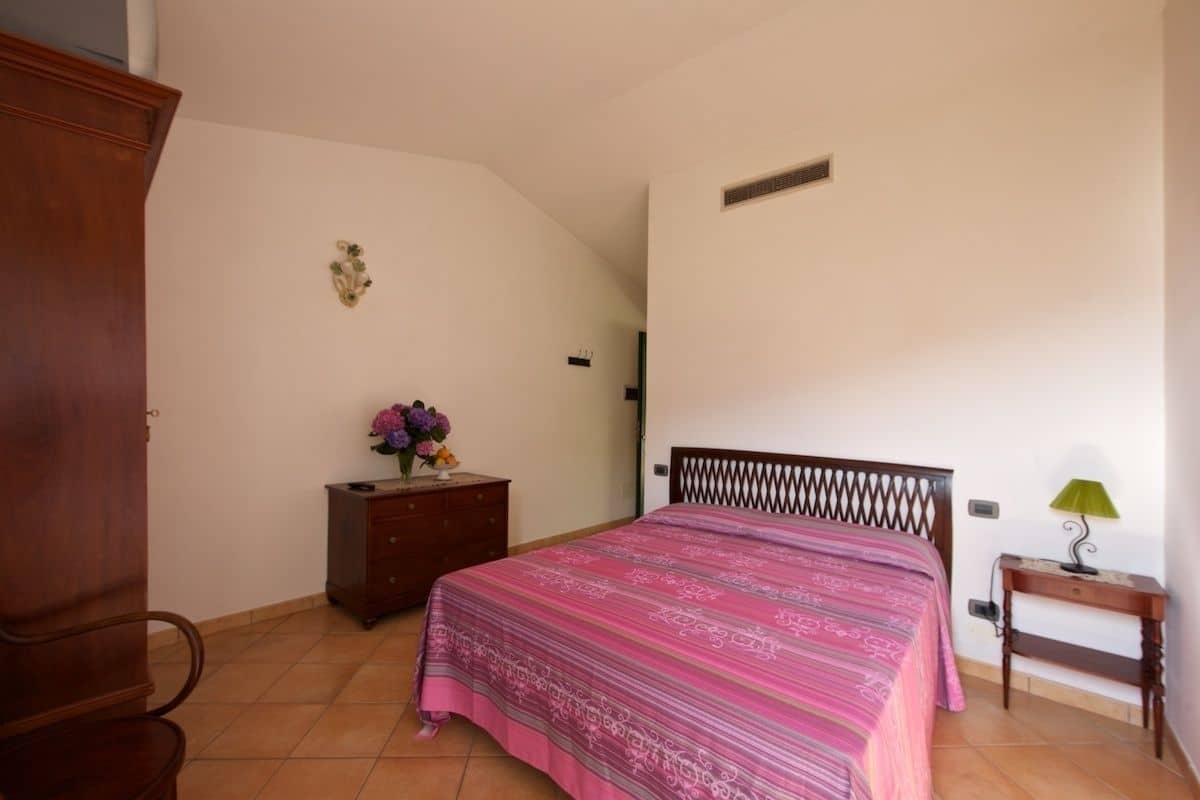 Une chambre à coucher comprenant un lit, une commode, une table de chevet et une lampe.