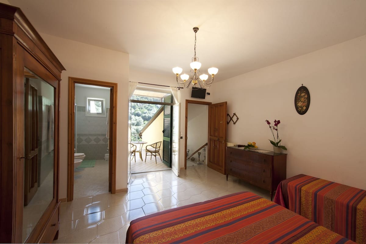 Une chambre d’hôtel avec un lit, une commode, un lustre et un balcon offrant une vue.