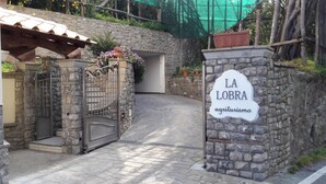 Une porte d’entrée en pierre surmontée d’une enseigne indiquant « LA LOBRA, hébergement à la ferme ».