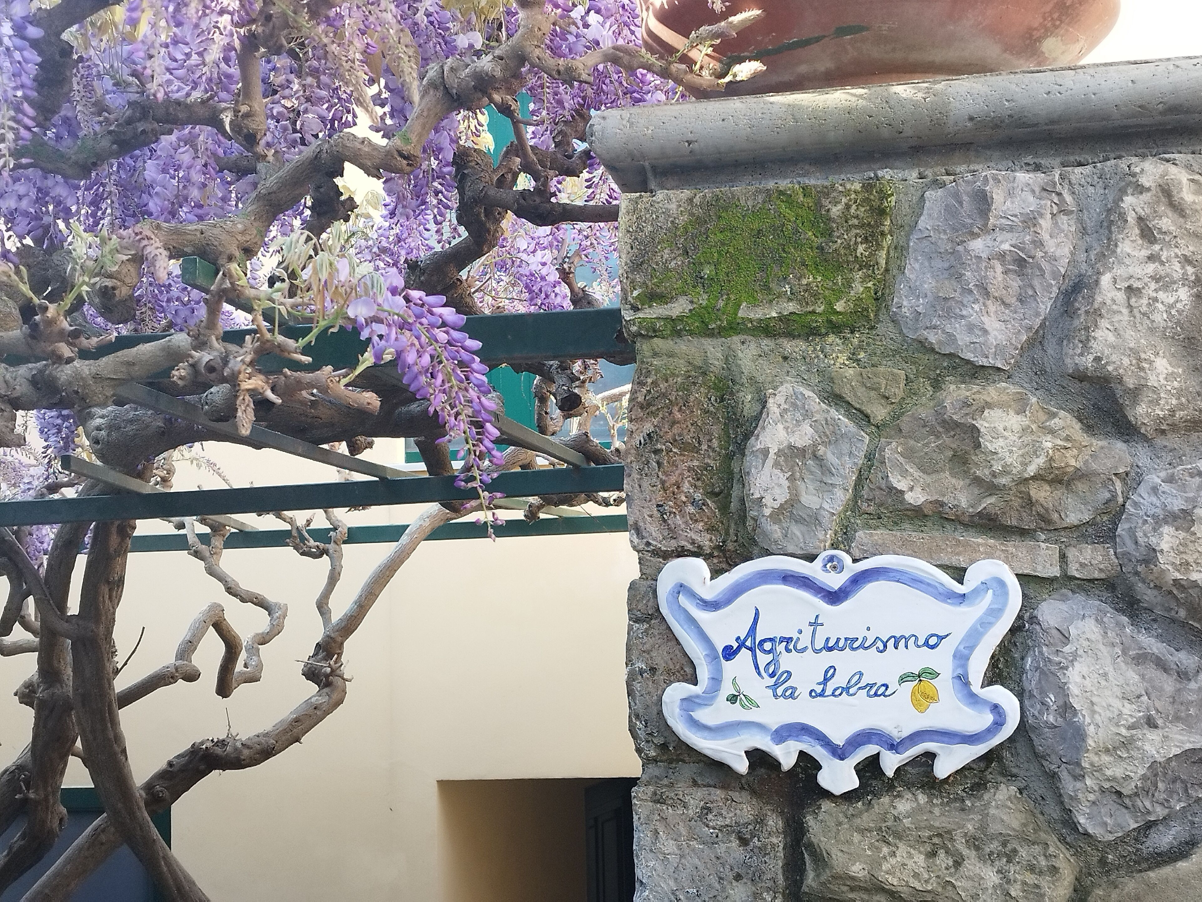 A stone wall with a sign reading "Agriturismo la Loba".