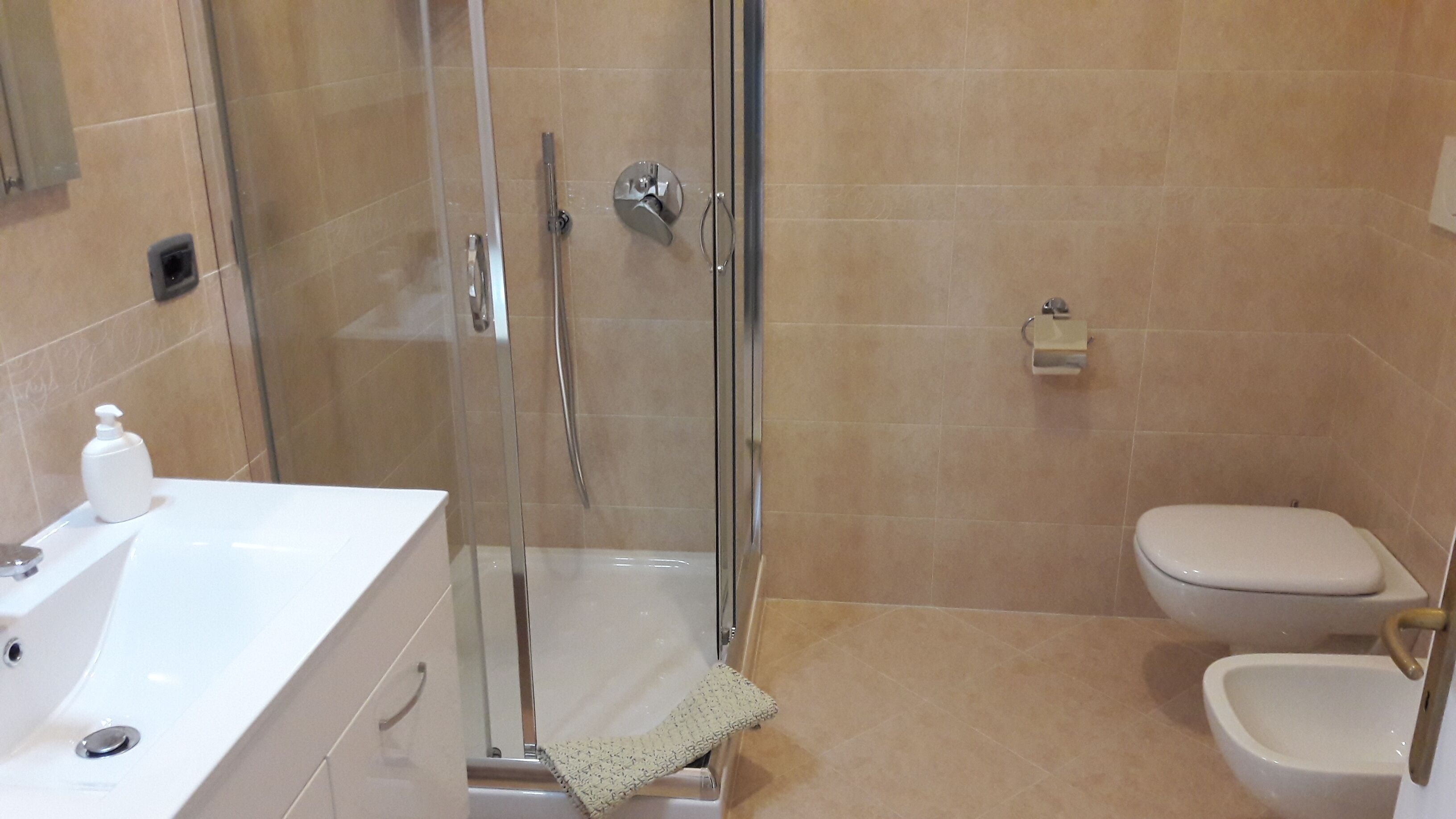 Une salle de bain avec une douche à parois de verre, des toilettes et un bidet.