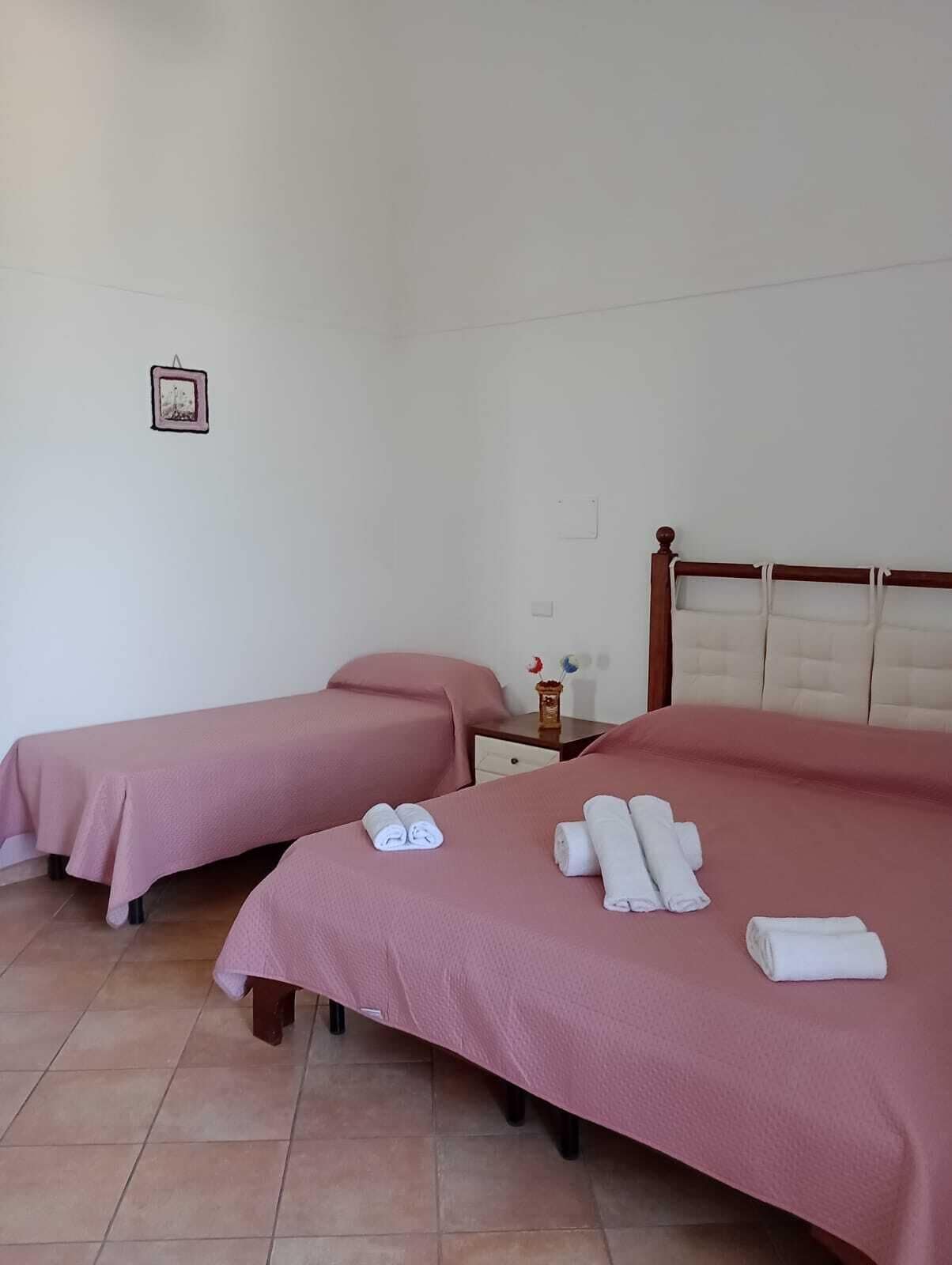 A hotel room with two beds, a nightstand, and a picture on the wall.