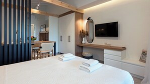 Un dormitorio moderno con una cama grande, un televisor montado en la pared y una viga de techo de madera.
