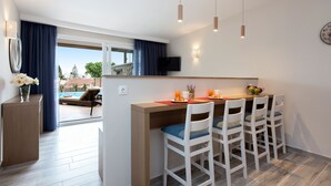 Cocina moderna con comedor, televisor montado en la pared y vistas al exterior.