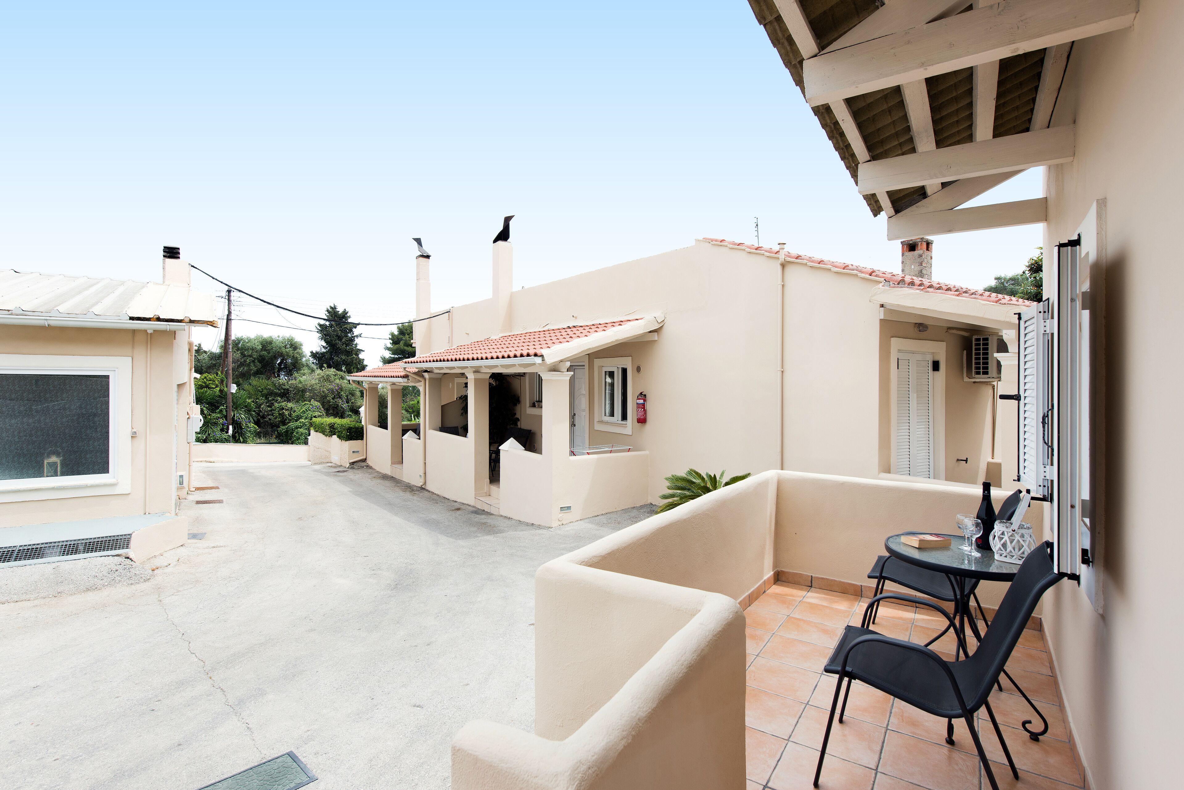 Un edificio residencial con un patio empedrado, una pequeña mesa con sillas y una puerta con ventana.