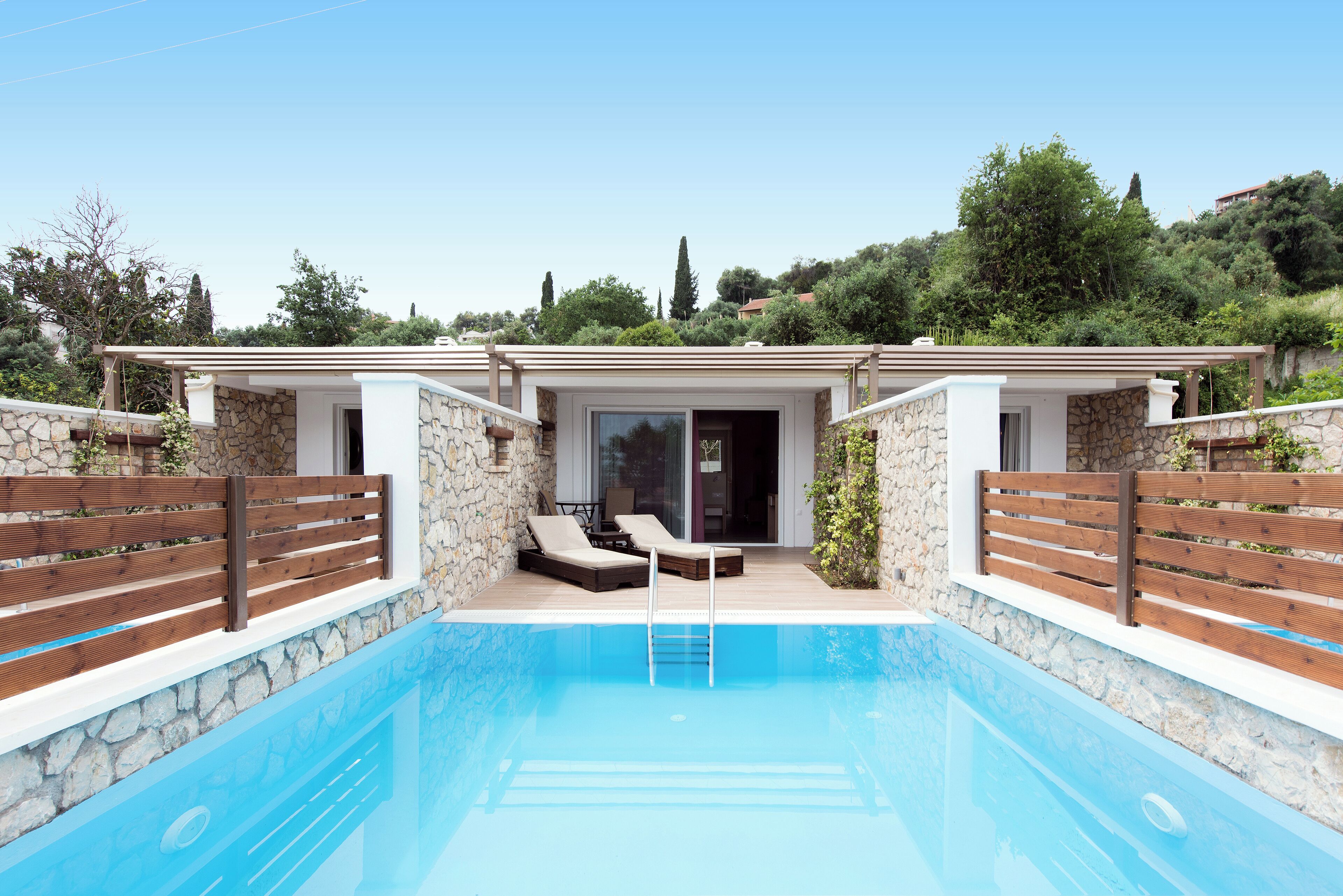 A swimming pool with two lounge chairs and a wooden deck.