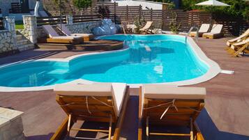Una piscina con sillas de descanso y sombrillas.