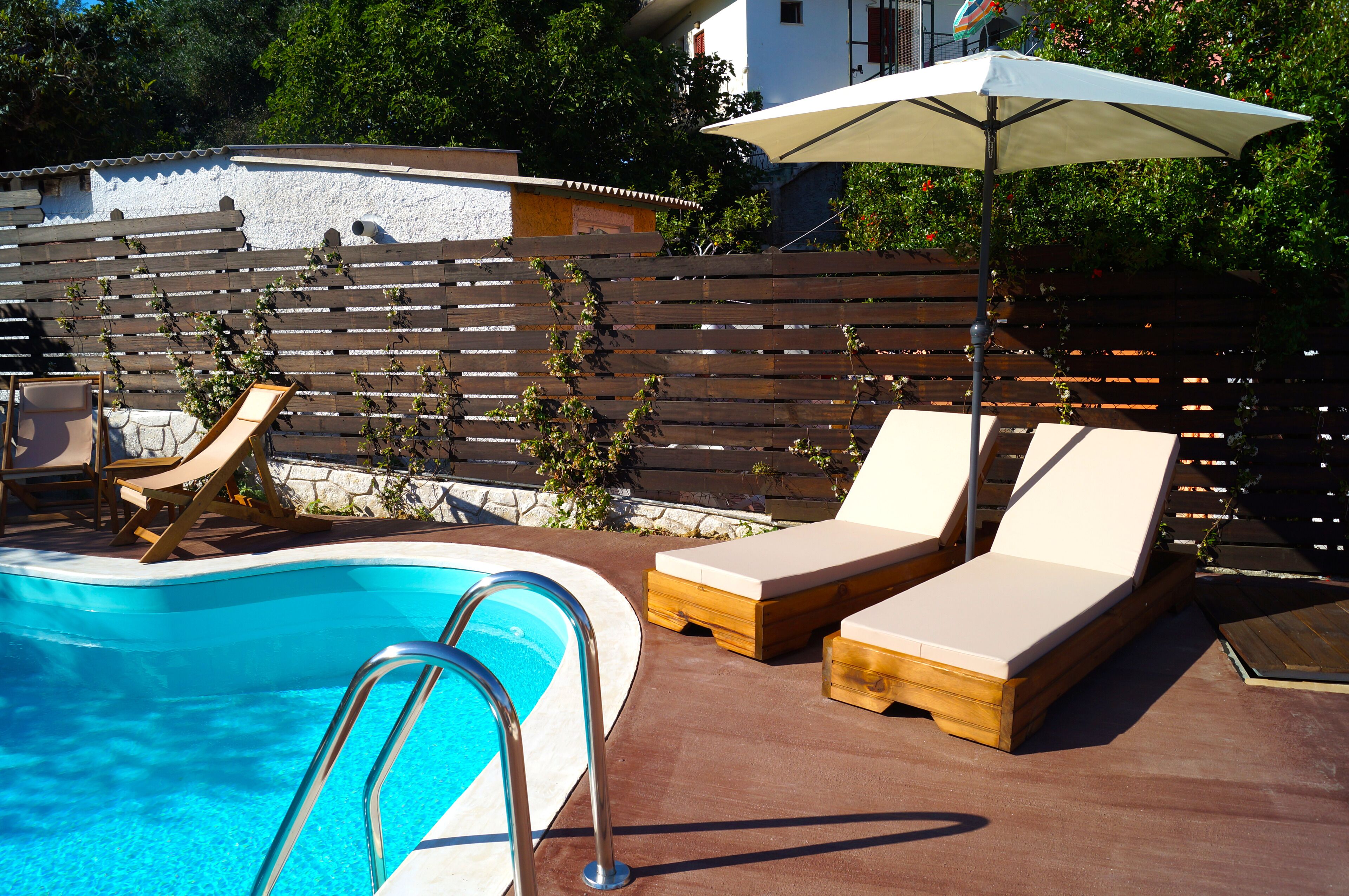A swimming pool with wooden loungers and a metal ladder.