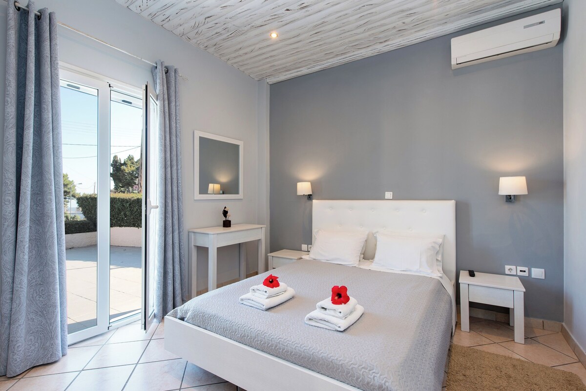 Un dormitorio moderno con una cama grande, dos mesitas de noche, una mesita auxiliar, un espejo y un equipo de aire acondicionado.