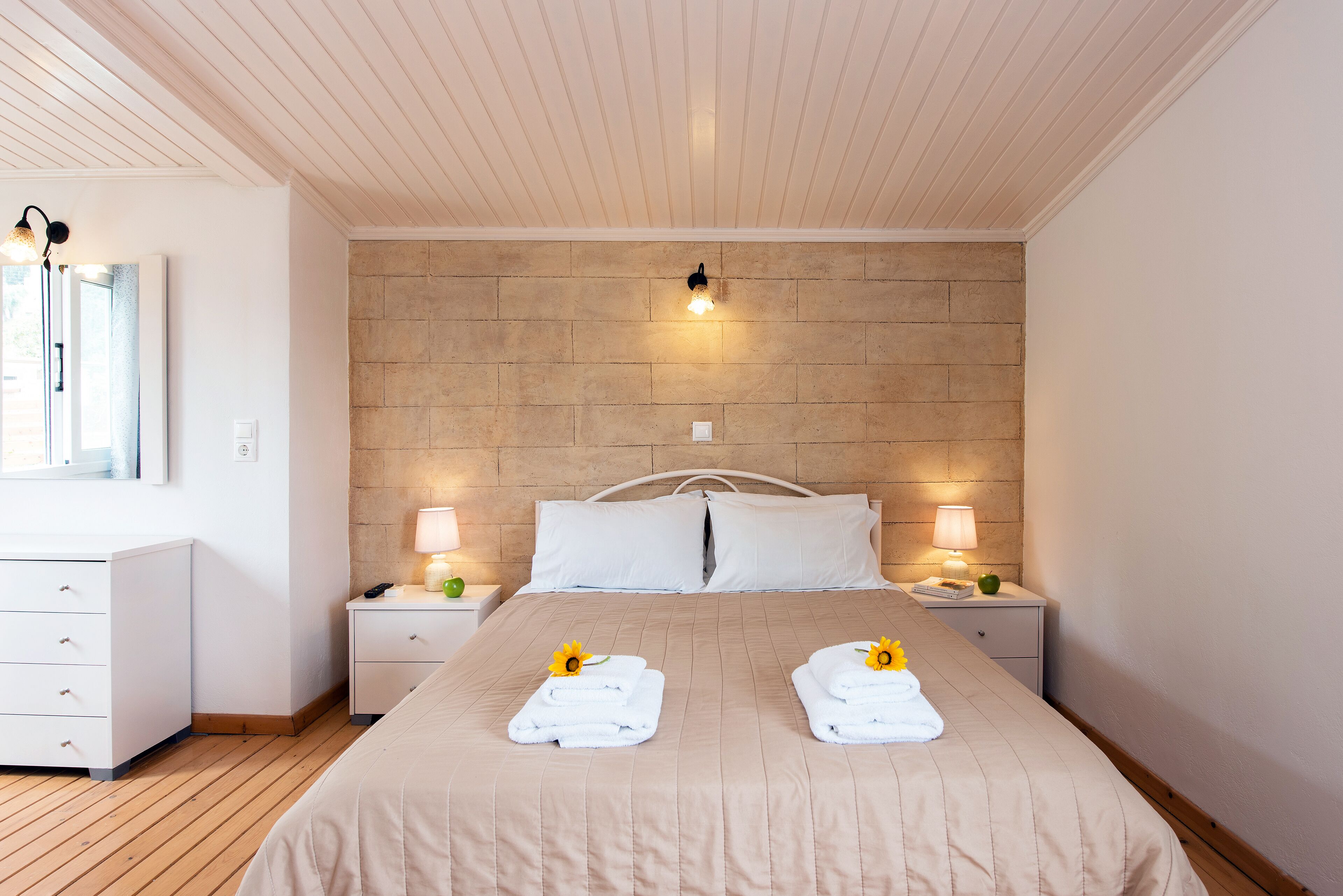 A neatly arranged bedroom with a large bed, two bedside tables, a nightstand, a dresser, and a mirror.