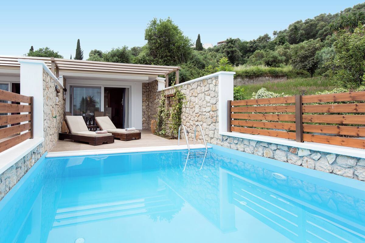 A pool area with lounge chairs and a stone wall.