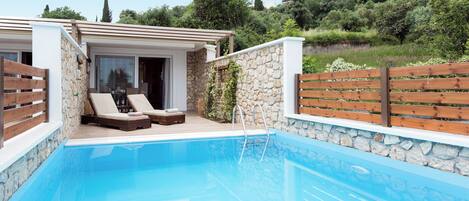A pool area with lounge chairs and a stone wall.
