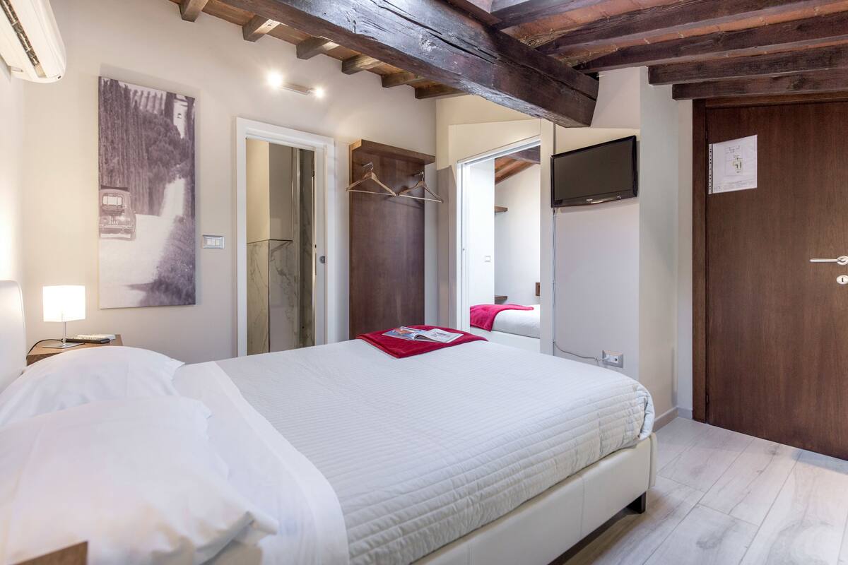A hotel room with a large bed, a wooden ceiling, a TV, and a door with a sign.