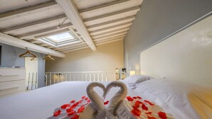 Una habitación de hotel con una cama, un tragaluz, un aparador blanco y una barandilla blanca.