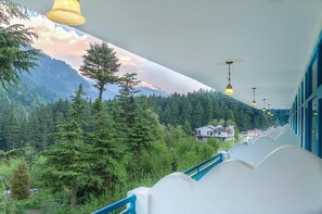 Ein Balkon mit Blick auf eine bewaldete Berglandschaft und ein Gebäude im Hintergrund.