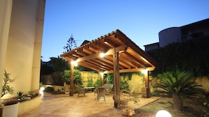 Un patio al aire libre con pérgola, asientos y plantas en macetas.