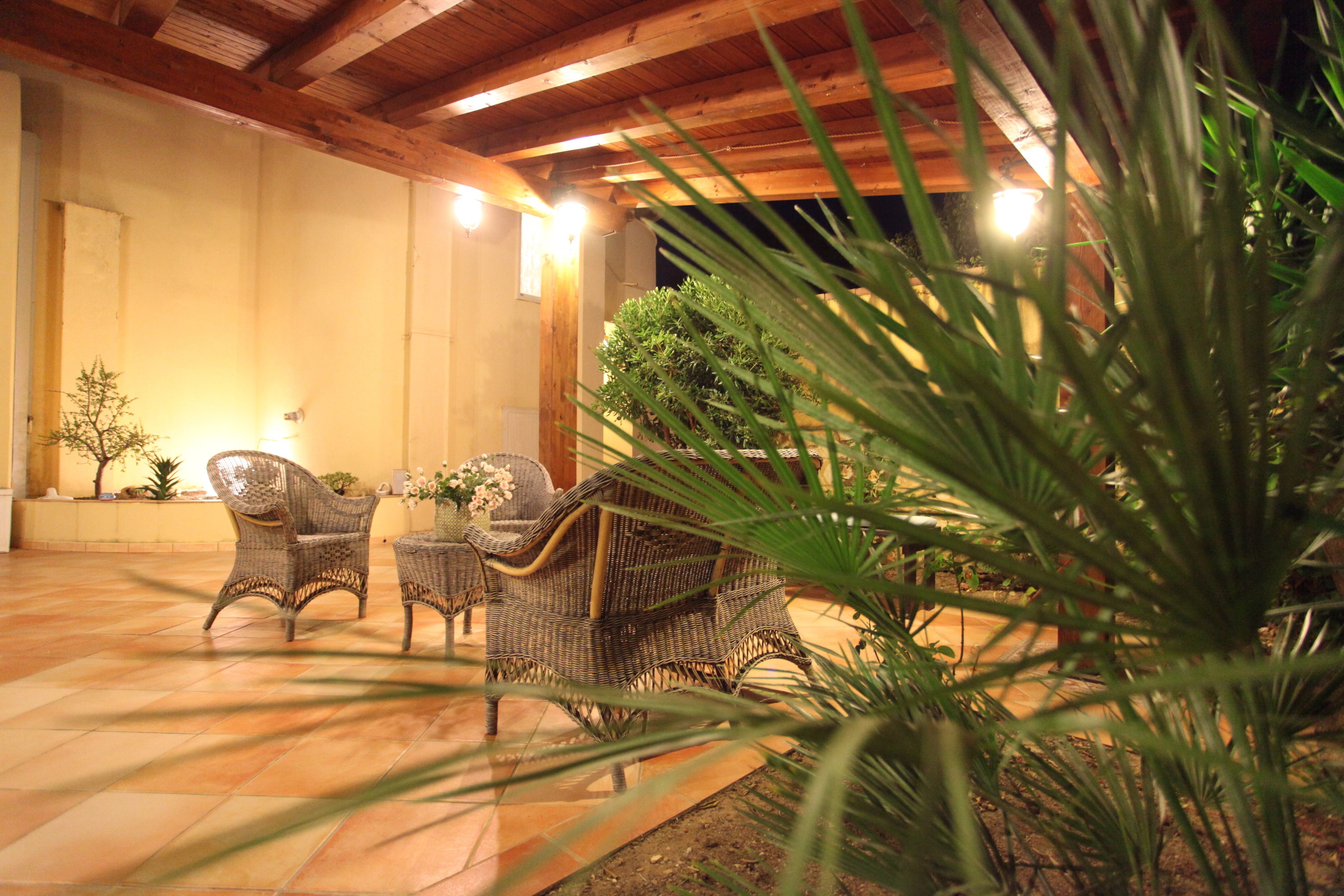 Un patio al aire libre con mobiliario de mimbre y una planta en maceta.