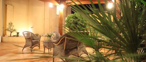 An outdoor patio with wicker furniture and a potted plant.