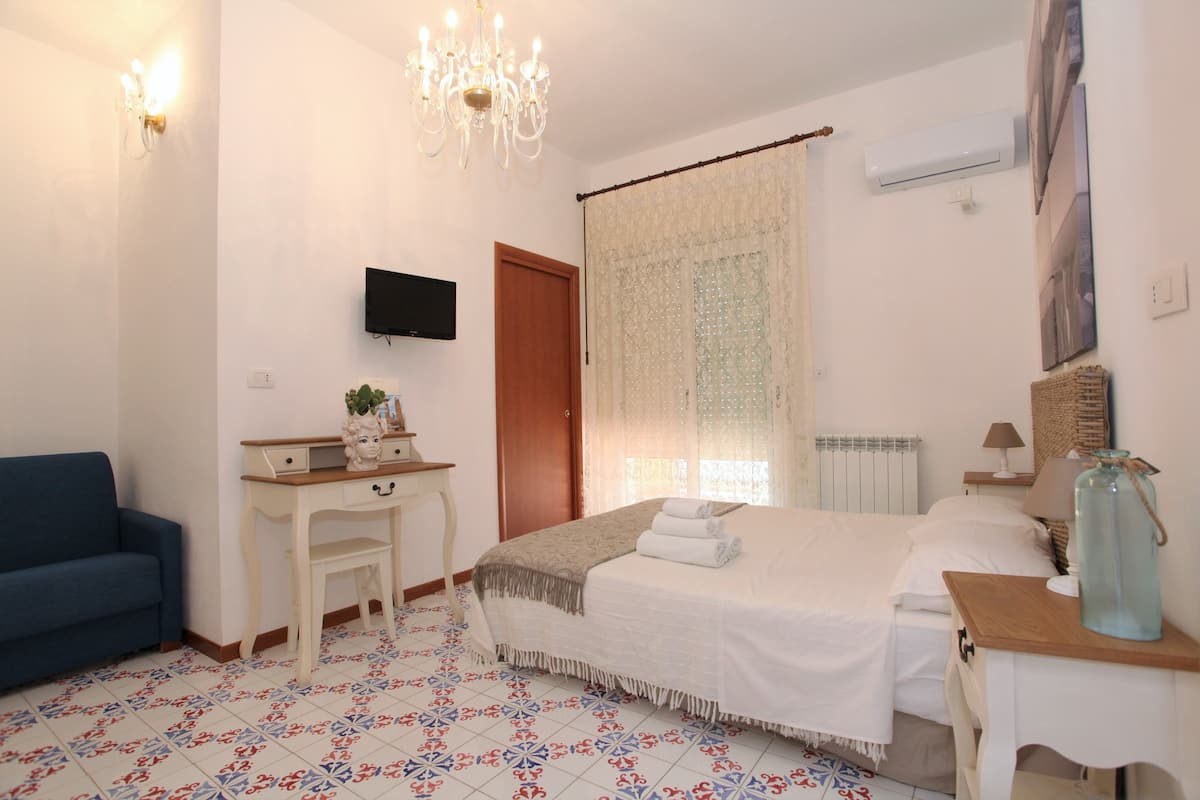 Une chambre à coucher avec un lit, un bureau, une chaise, une télévision et un lustre.