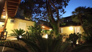Un patio con pérgola, plantas en macetas y un área de estar exterior bien iluminada.