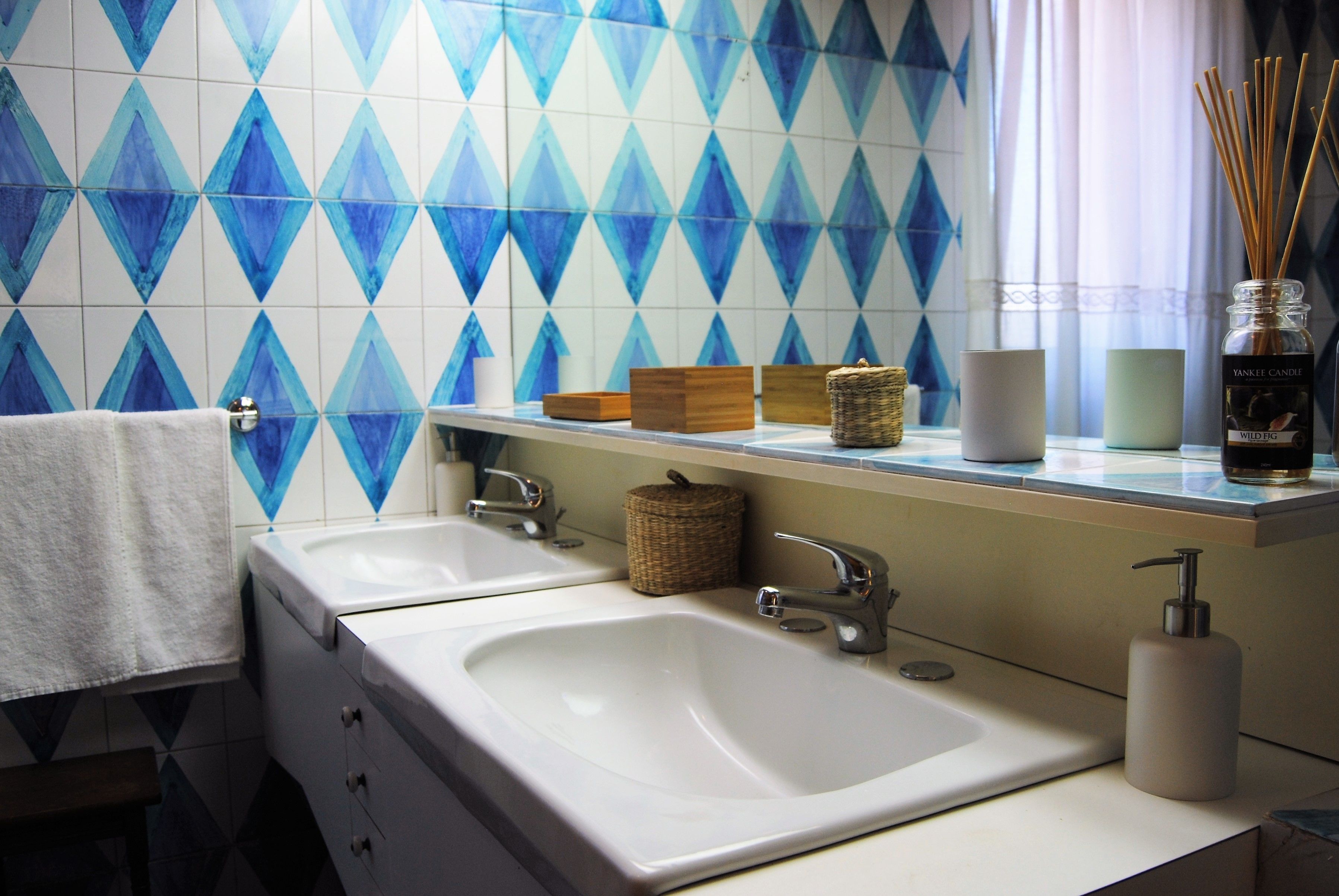 A bathroom with two sinks, a mirror, and a window with curtains.