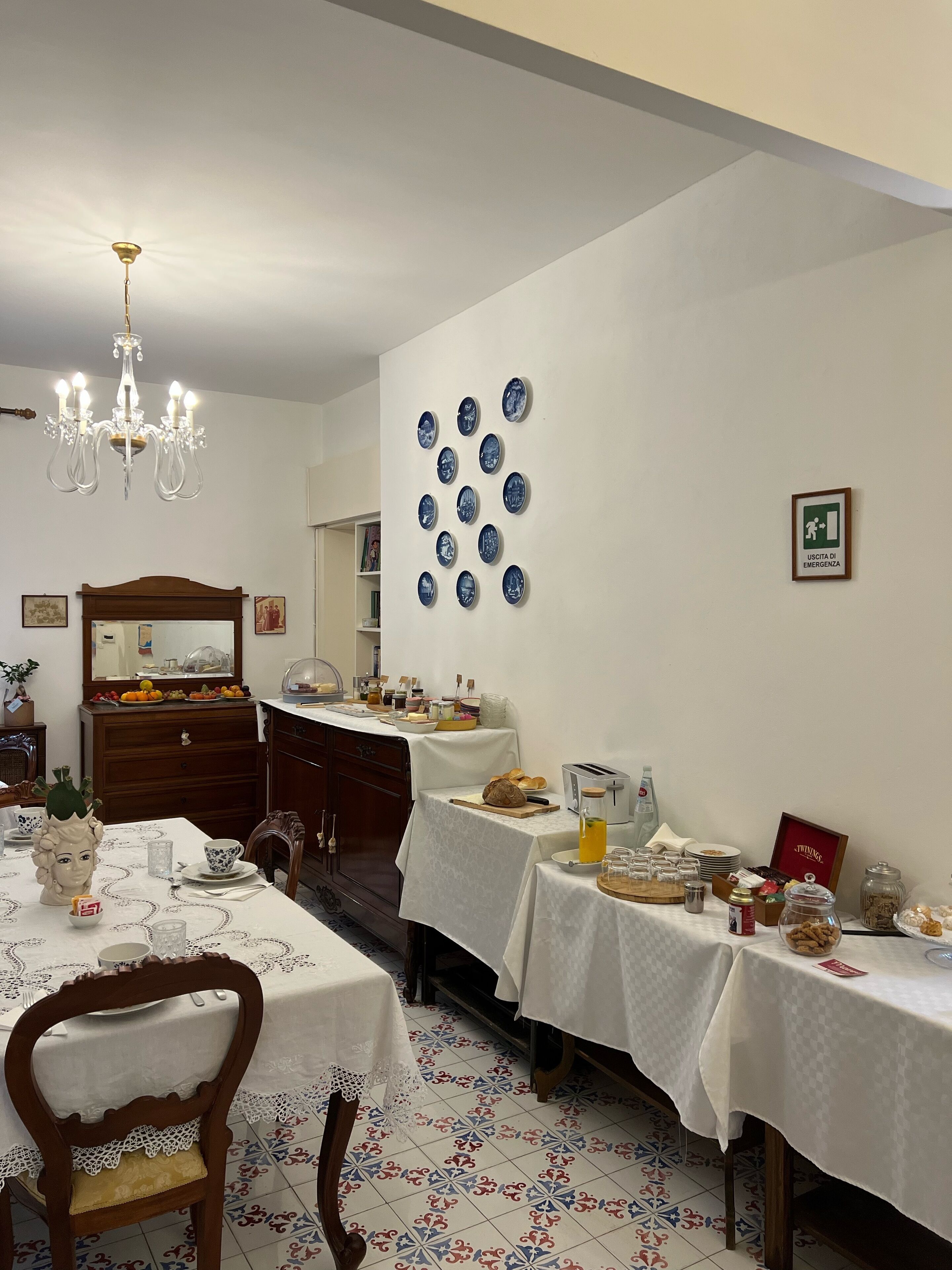 Un espace repas agrémenté d’un lustre, un mur avec un panneau indiquant la sortie de secours et un buffet.