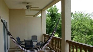 A balcony with a hammock, a table, and chairs. - Sunset Villas 12I (Roatan)