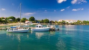 A marina with two boats docked, calm water, and a clear sky. - Sunset Villas 12I (Roatan)