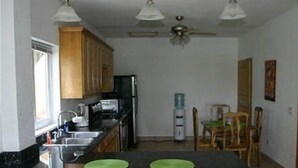 A kitchen with wooden cabinets, a refrigerator, a microwave, and a water dispenser. - Sunset Villas 12I (Roatan)