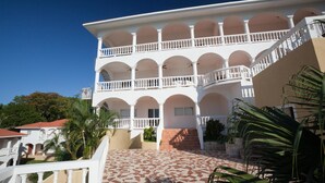 Un edificio de varios pisos con fachada blanca, varios balcones y un patio empedrado.
