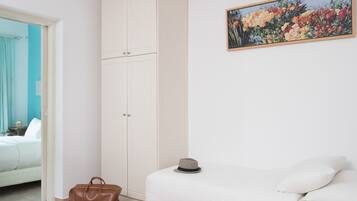 A bedroom with a bed, a wardrobe, a painting, and a handbag.