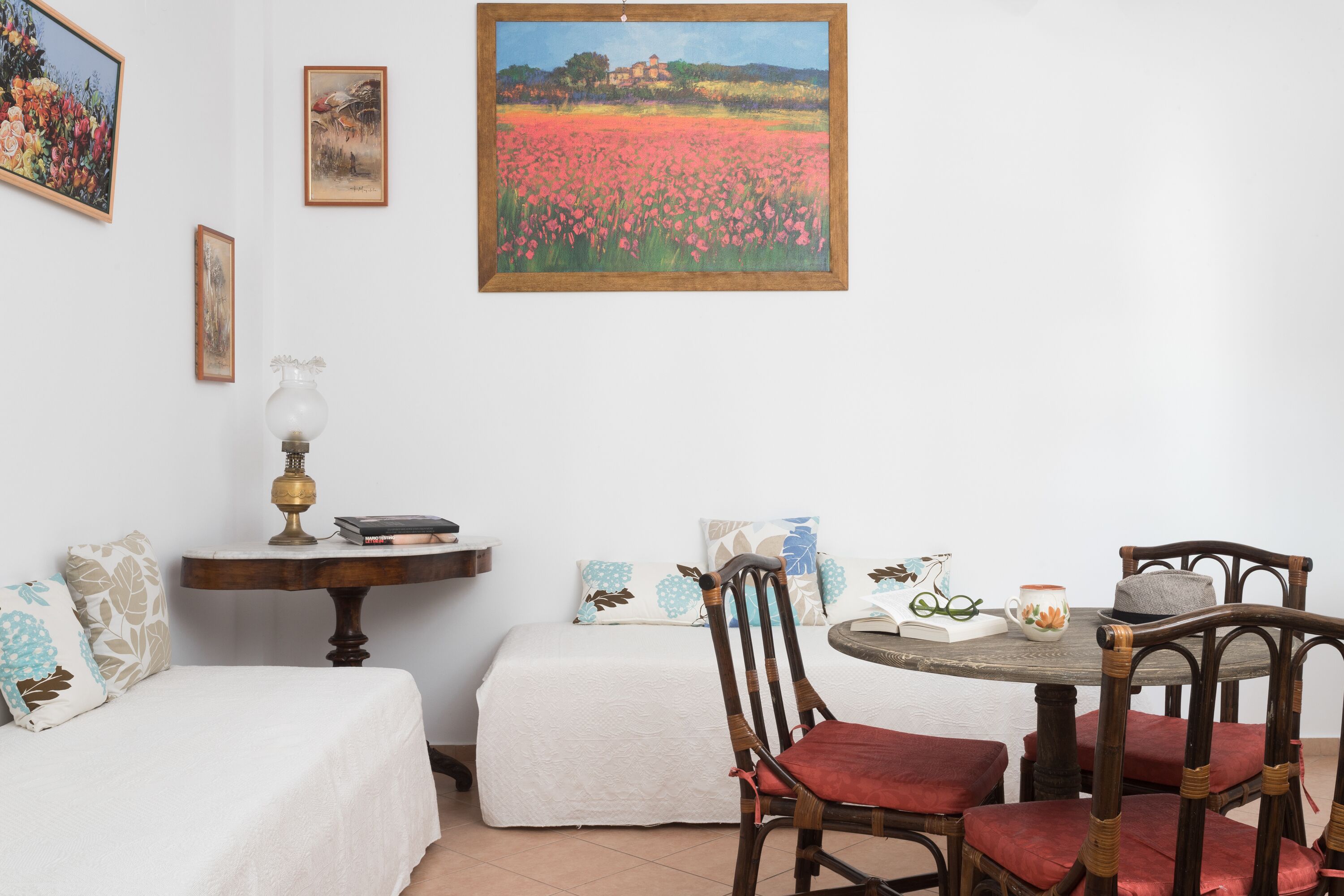 A room with a bed, a table with chairs, and a painting on the wall.