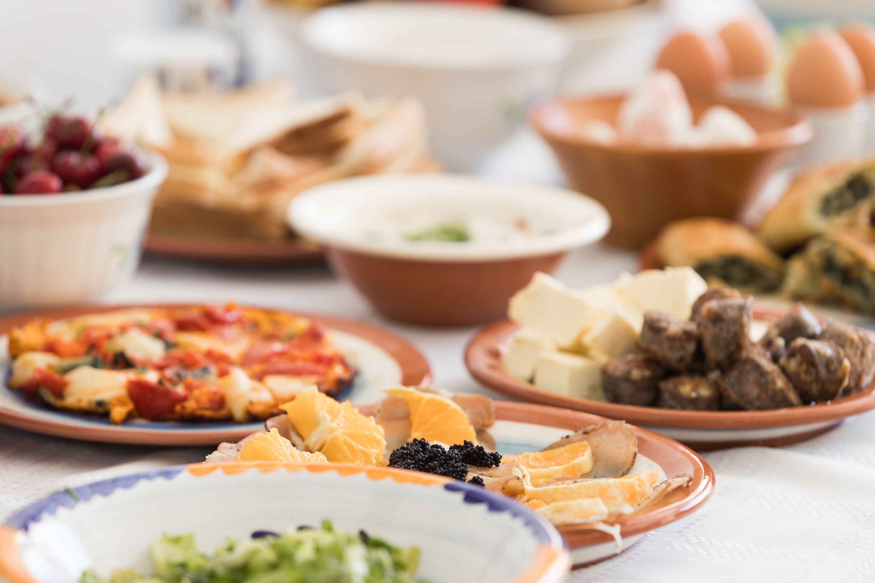 A variety of dishes on a table, including pizza, cheese, and other foods.