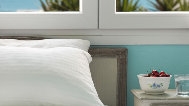 Une chambre avec un lit, une table de chevet, un panier de fruits et une vue sur la mer.